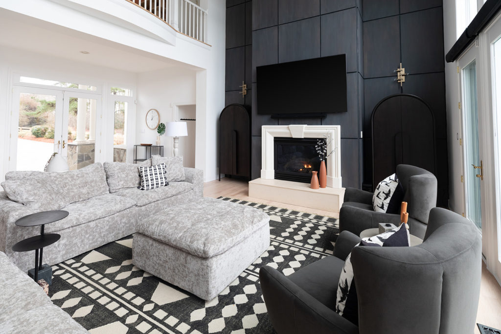 An award winning living room design featuring two dark grey chairs to the right and a light grey sofa to the left done by the TEW Design Studio team in Apex