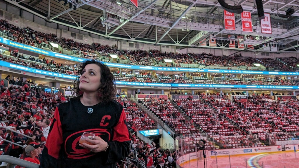TEW Design Member at a Carolina Hurricanes Game At PNC Arena in Raleigh NC with TEW Design advertisement on video board behind them