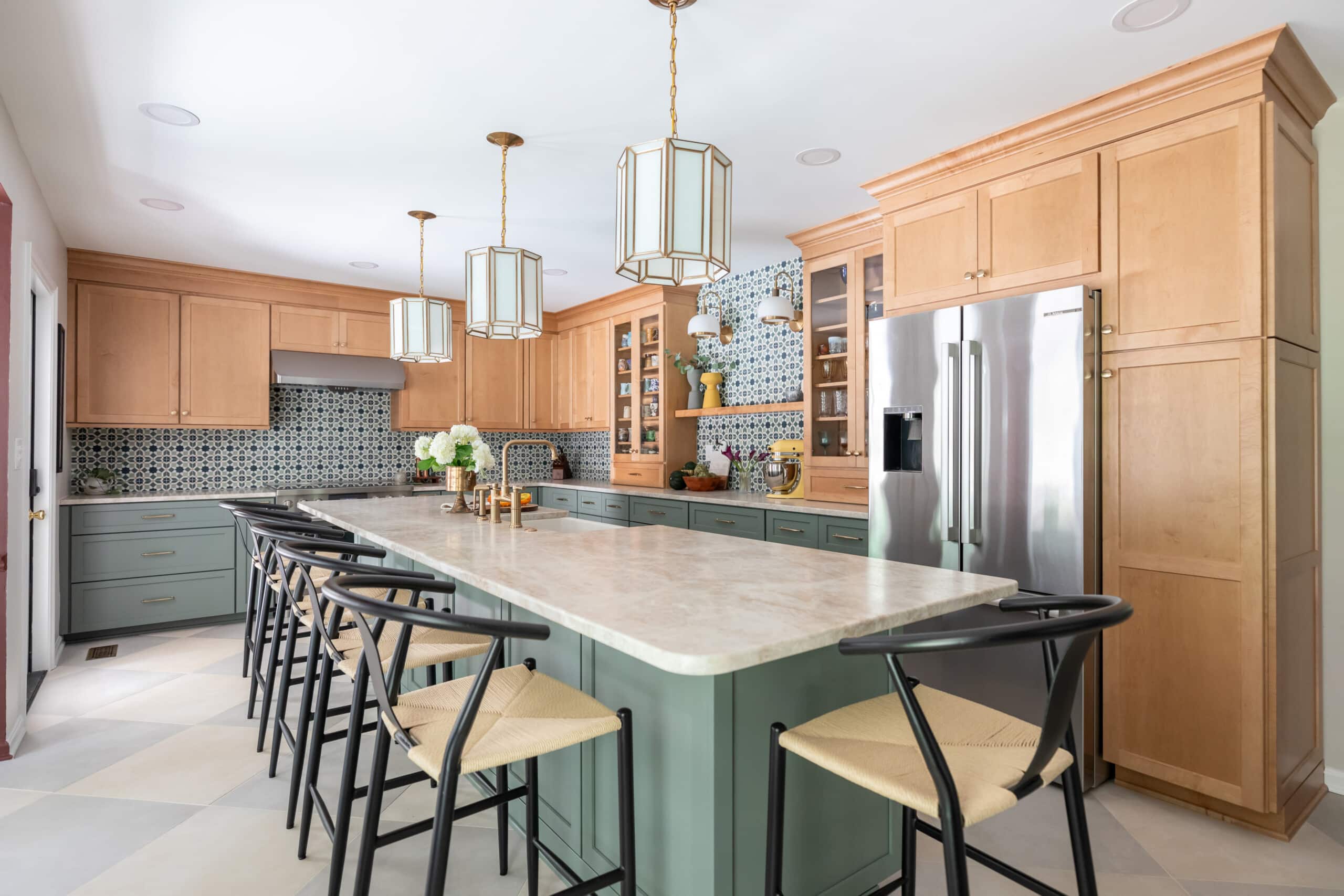 Diagonal view of kitchen showcasing light fixtures, brass hardware, natural textures and earth tones.