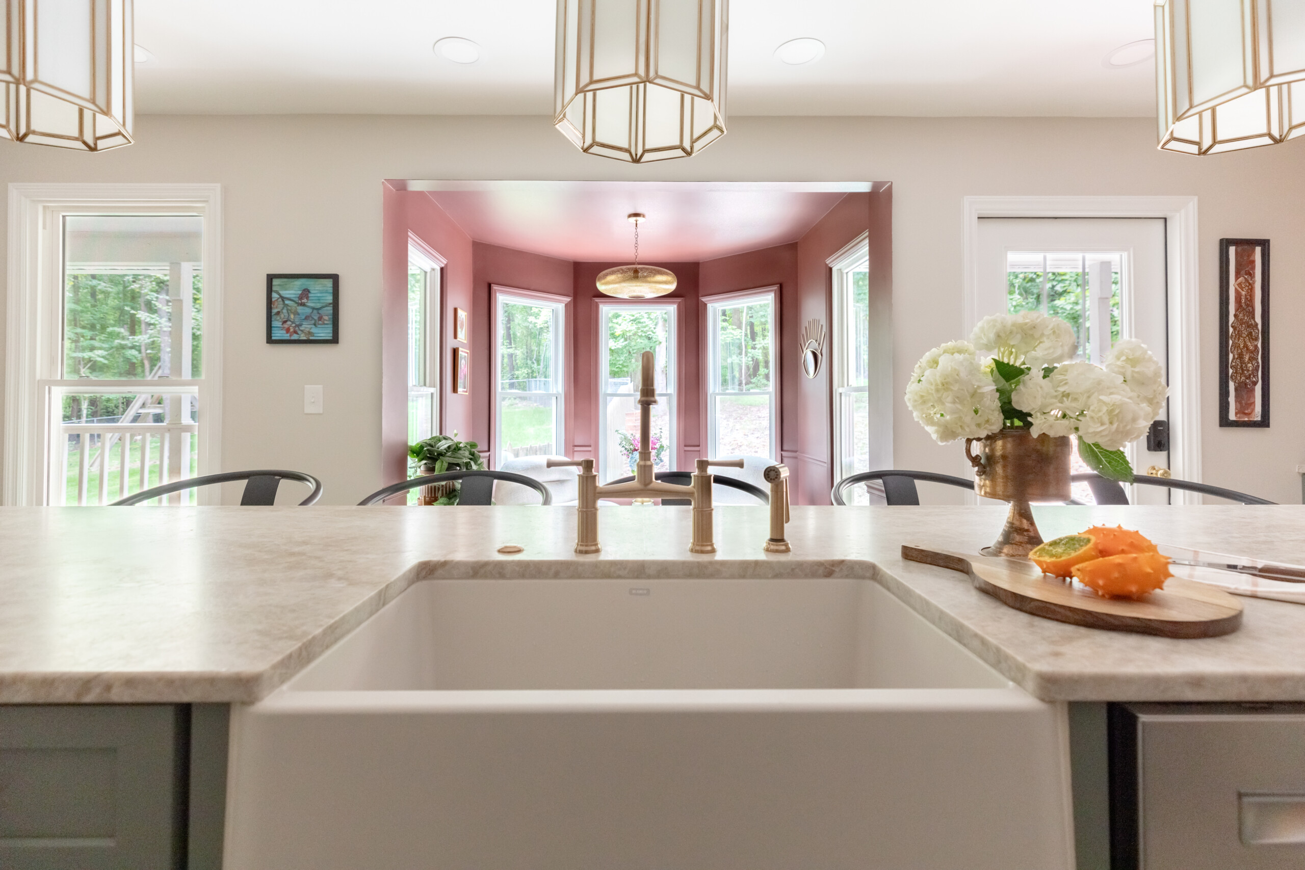 Peek into breakfast nook viewing from farmhouse sink and brass fixtures.