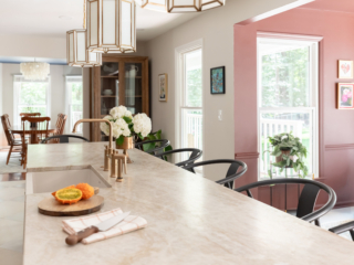TEW DESIGN STUDIO | HEATHER RIDGE KITCHEN Length-wise view of elegant kitchen remodel highlighting brass fixtures and a cozy breakfast nook.
