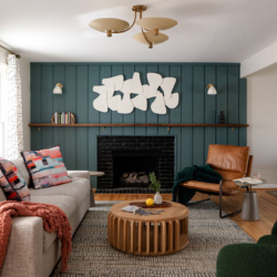Modern Raleigh living room with green vertical paneling, sculptural white wall art, black fireplace, and colorful abstract accents.