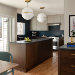 Modern Raleigh kitchen design with globe pendant lights, two-tone cabinetry, a matte blue tile backsplash, and styled with fresh fruit.