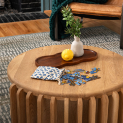 Modern Raleigh living room with natural wood coffee table, styling accessories, a warm leather chair and a green, chunky knit blanket.