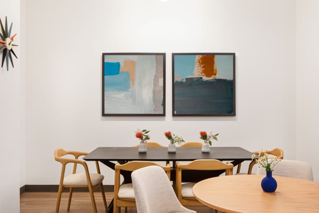 Wall art and a large table with chairs in workplace breakroom designed for employee wellness - TEW Design Studio
