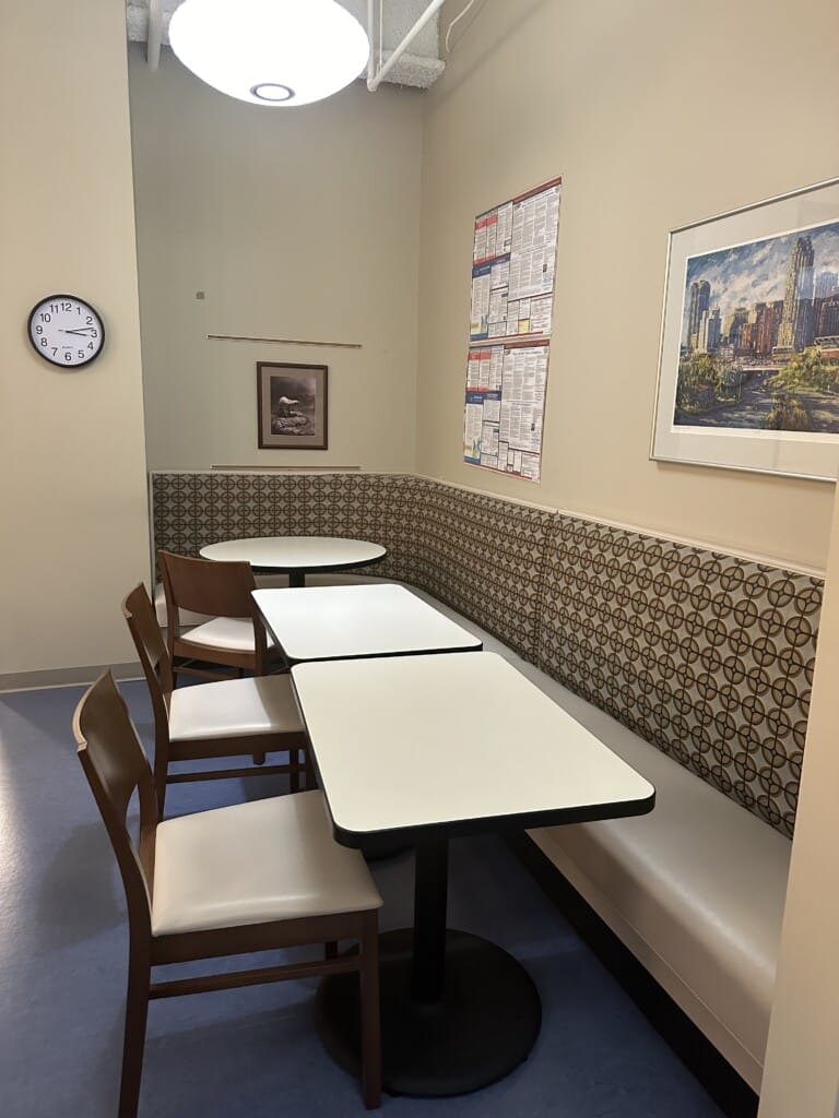 Long booth with tables and chairs opposite in the workplaces breakroom designed for employee wellness - TEW Design Studio
