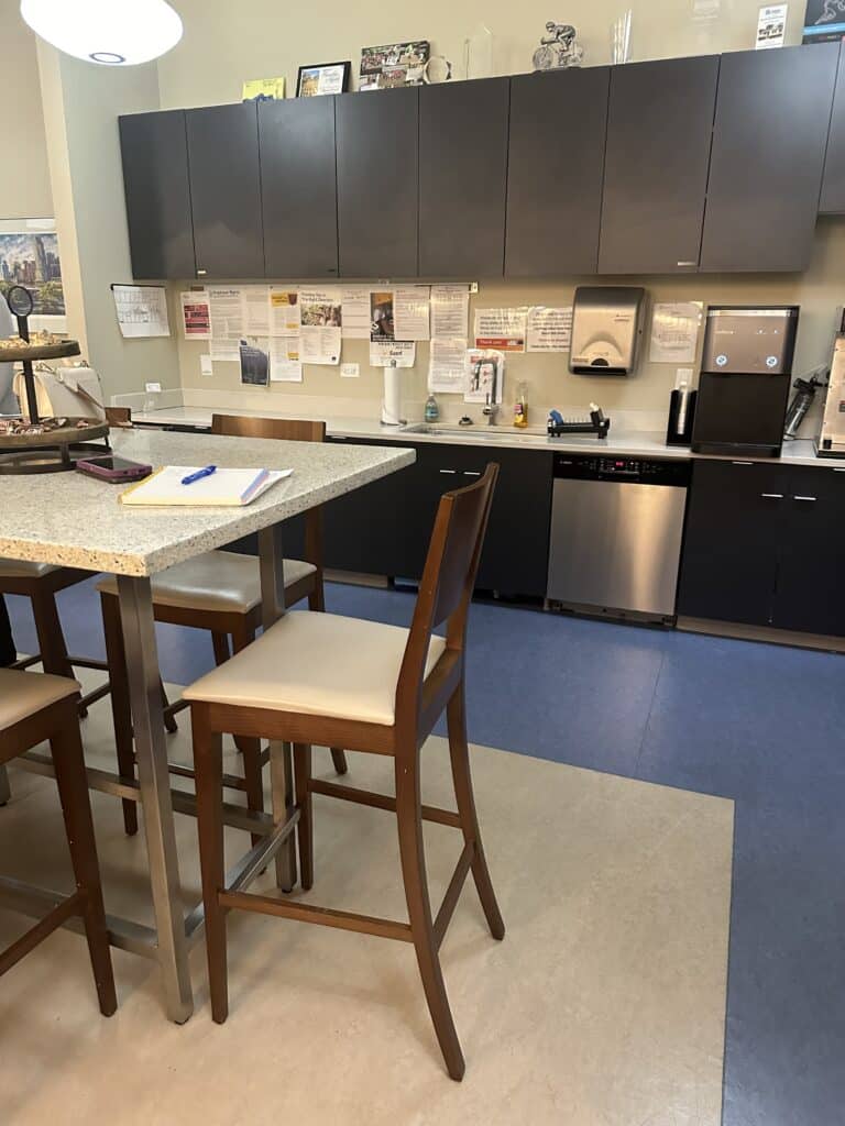 High-top table and cabinetry in workplace breakroom designed for employee wellness - TEW Design Studio